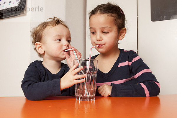 Junge und Mädchen trinken Wasser mit Strohhalmen