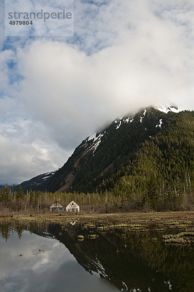 Alte Eyak Stadt mit Chugach Mountains reflektieren in einem Teich entlang der Copper River Highway  Chugach National Forest  Cordova  South Central Alaska  Frühling