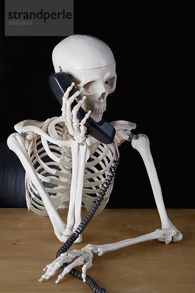 Ein Skelett mit einem Festnetztelefon