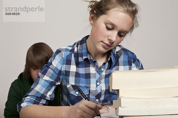 Ein Teenager-Mädchen bei der Klassenarbeit  Junge im Hintergrund