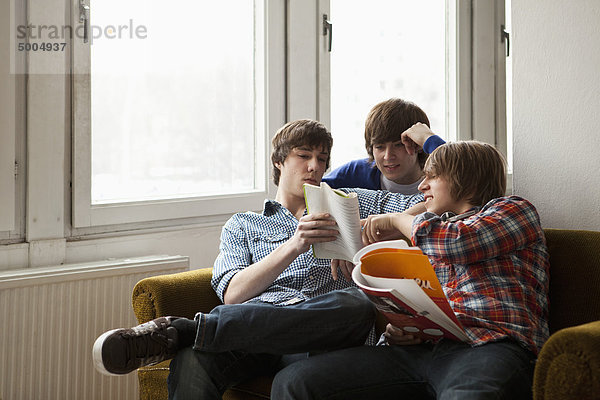 Drei Freunde  die zusammen in einem Wohnzimmer studieren.