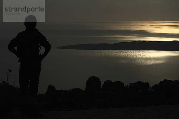 Eine Silhouette einer Frau mit Blick auf das Adriatische Meer bei Unije  Kroatien