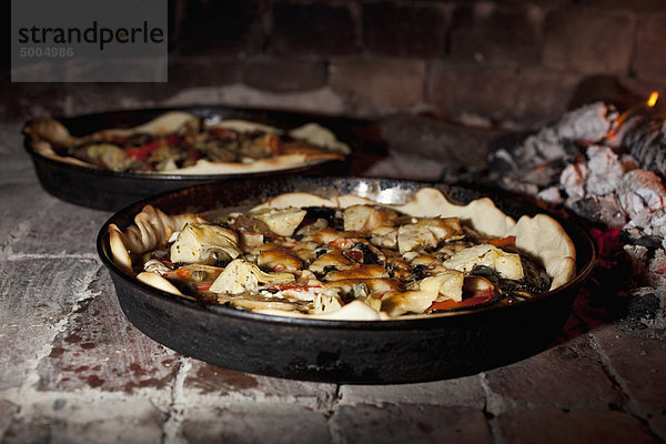 Pizzas beim Kochen im Steinofen