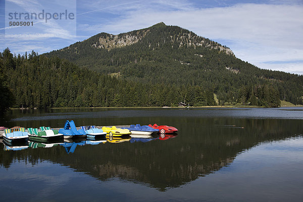 Tretboote auf einem See und einem Berg im Hintergrund