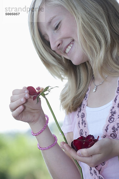 Ein junges Mädchen  das Blütenblätter von einer Blume pflückt.