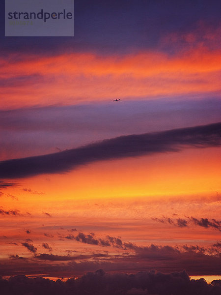 Ein Flugzeug fliegt in den Himmel  wenn die Sonne untergeht.