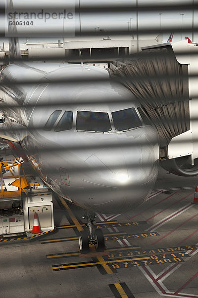 Blick durch ein Fenster eines mit einer Fluggastbrücke verbundenen Flugzeuges