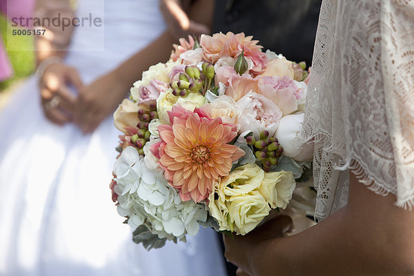 Detail einer Frau  die bei einer Hochzeit einen Blumenstrauß hält.