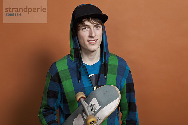 Ein Teenager mit Skateboard  Porträt  Studioaufnahme