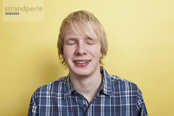 Ein lächelnder Teenager mit geschlossenen Augen  Porträt  Studioaufnahme