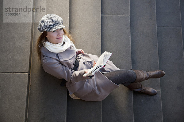 Frau draußen auf der Treppe mit Buch