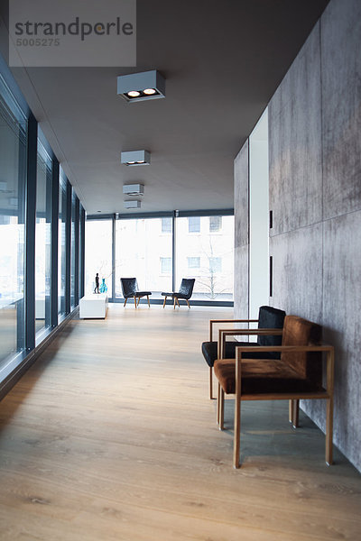 Halle in moderner Wohnung mit Holzboden und leeren Stühlen.
