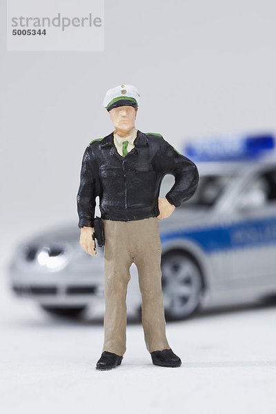 Eine Miniatur-Polizistenfigur neben einem Miniatur-Polizeiwagen