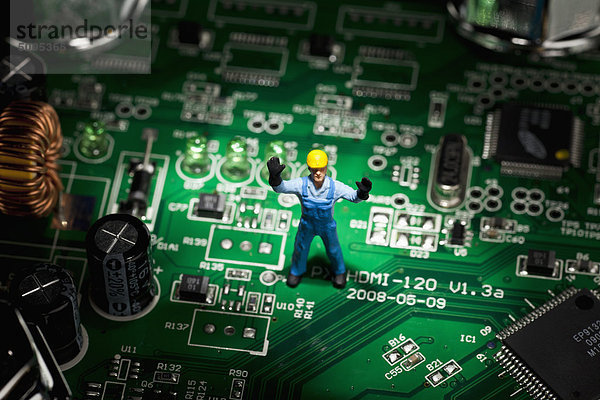 Ein Miniatur-Figurenbauarbeiter  der auf einem Computer-Motherboard steht.