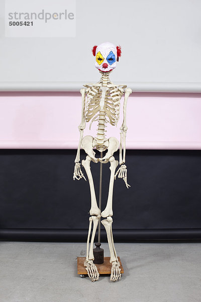 Stehendes Skelett mit Clownmaske.