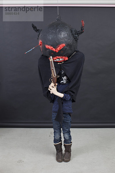 Kind mit Halloween-Outfit und Pistole.