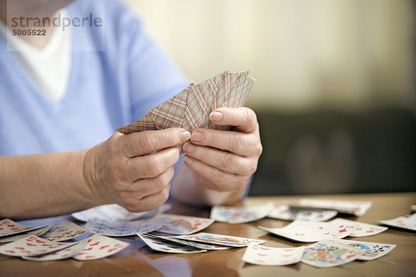 Eine ältere Frau beim Kartenspielen  Mittelteil  Konzentration auf die Hände