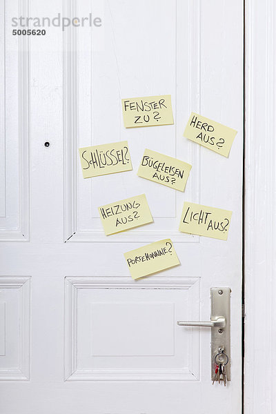 Haftnotizen an einer Haustür mit verschiedenen Erinnerungen in Deutsch