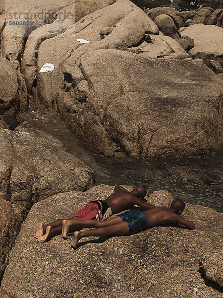 Zwei Männer beim Sonnenbaden auf einem großen Felsen am Bach