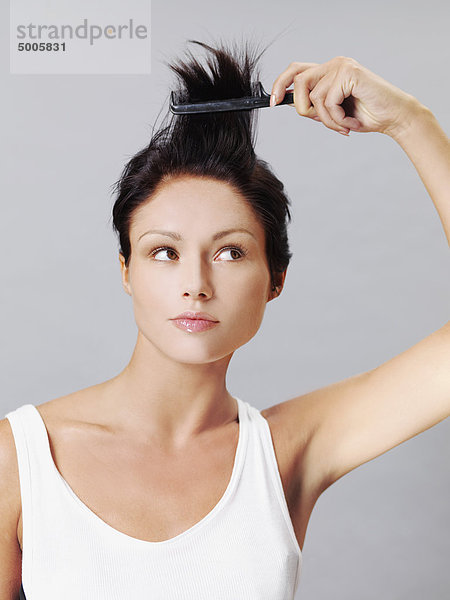 Eine Frau kämmt sich spielerisch die Haare.