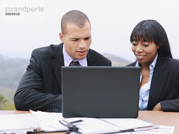 Ein Geschäftsmann und eine Geschäftsfrau  die zusammen einen Laptop benutzen.