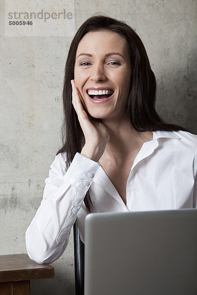 Eine Geschäftsfrau mit einem Laptop  die lacht.