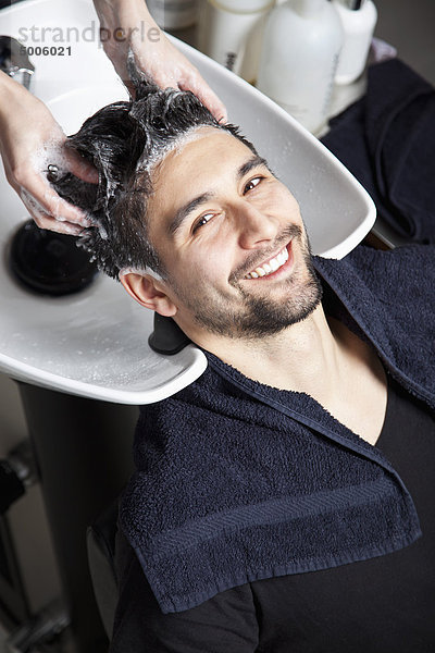 Ein Mann  der seine Haare in einem Friseursalon waschen lässt.