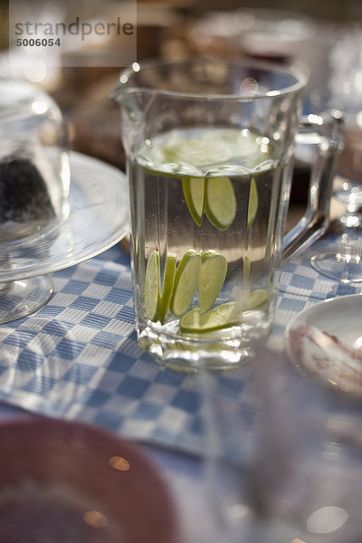 Wasserkrug mit Limettenscheiben auf dem Esstisch im Freien