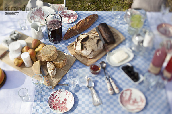 Käseräder  Brot und viel Geschirr auf einem Esstisch im Freien