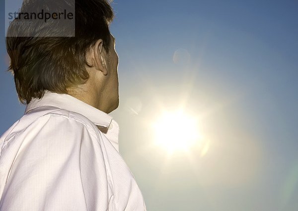 Mann im Freien schaut zur Sonne