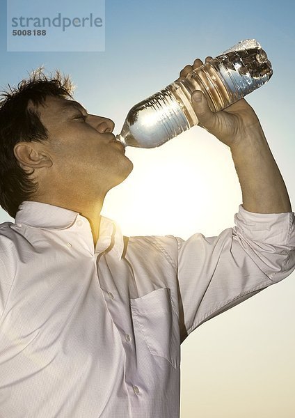 Mann im Freien trinkt aus einer Wasserflasche