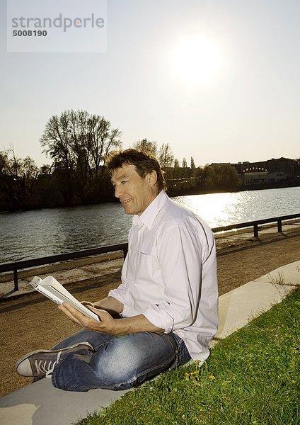 Man liest ein Buch am Ufer