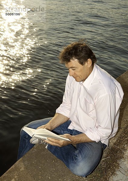 Man liest ein Buch am Ufer