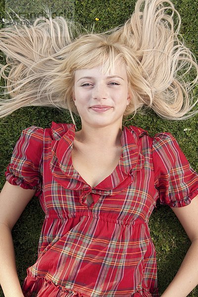 Lächelnde blonde Frau liegt im Gras