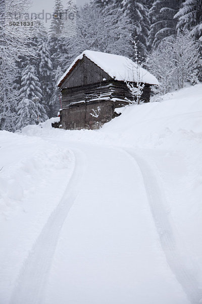 Reifenspuren bis zum Haus auf dem Hügel in winterlicher Landschaft