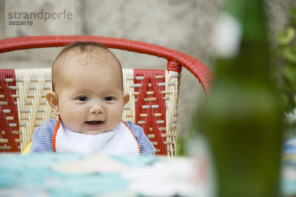 Baby sitzend auf einem Stuhl lächelnd