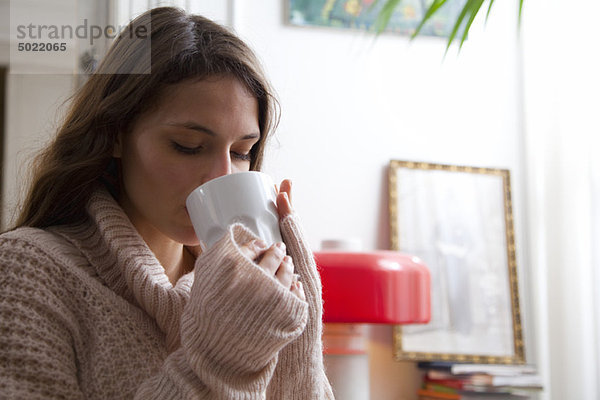 Junge Frau genießt zu Hause eine Tasse Kaffee