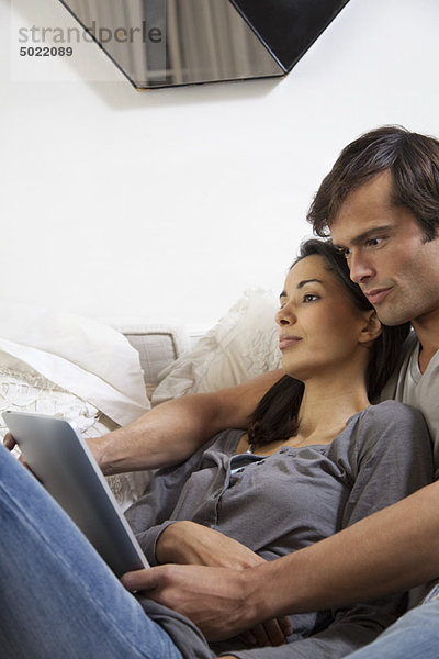 Paar entspannt zusammen  Mann schaut auf digitales Tablett