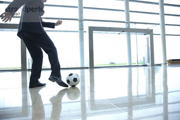 Geschäftsmann tritt Fußball in der Lobby