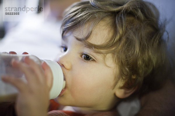 Kleinkind Junge trinkt Milch aus der Babyflasche