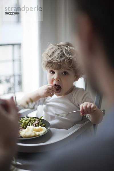 Kleinkind Junge beim Essen  Blick auf die Eltern im Vordergrund