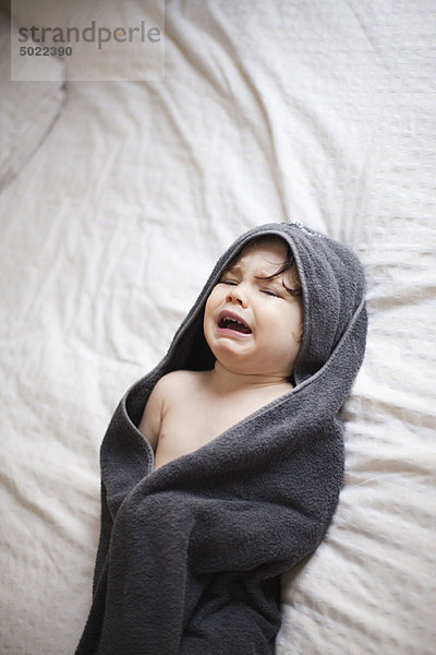 Weinendes Kleinkind in ein Handtuch gewickelt nach dem Baden