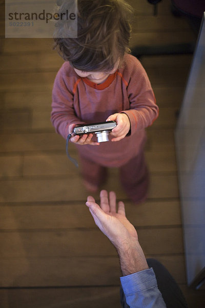 Kleinkind Junge schaut auf Digitalkamera  Draufsicht