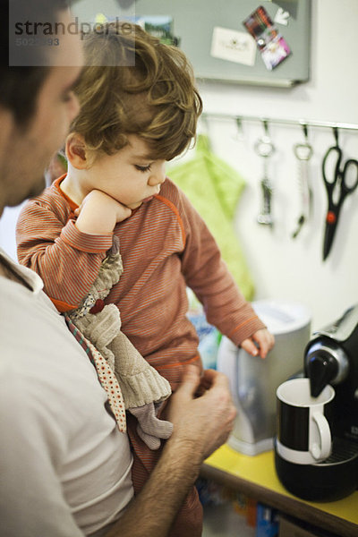 Vater hält jungen Sohn bei der Zubereitung des Espresso in der Hand