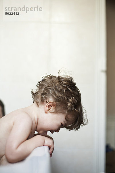 Kleinkind Junge lehnt über die Seite der Badewanne weinend