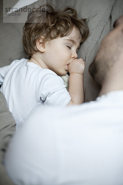 Kleinkind Junge schläft neben Vater  abgeschnitten