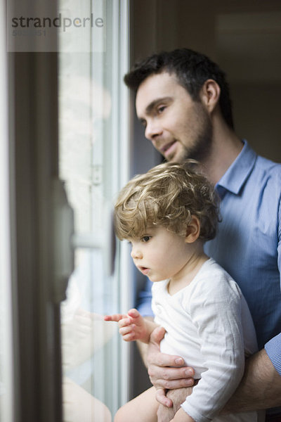 Vater und Kleinkind Sohn schauen aus dem Fenster  Portrait