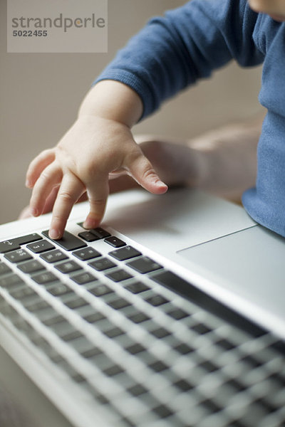 Kinderhand berührt Laptop-Tastatur