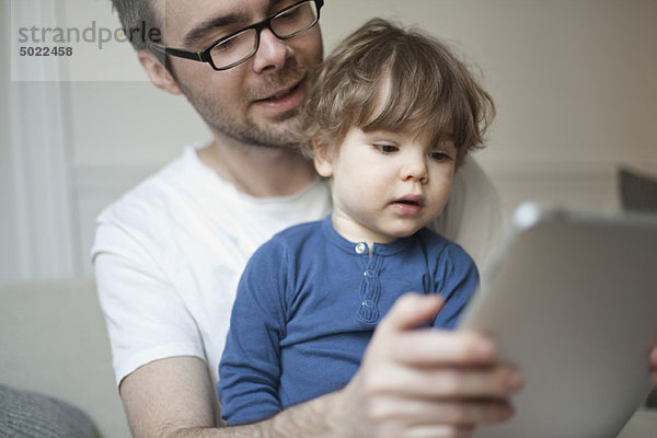 Kleinkind Junge beobachtet Vater mit digitalem Tablett