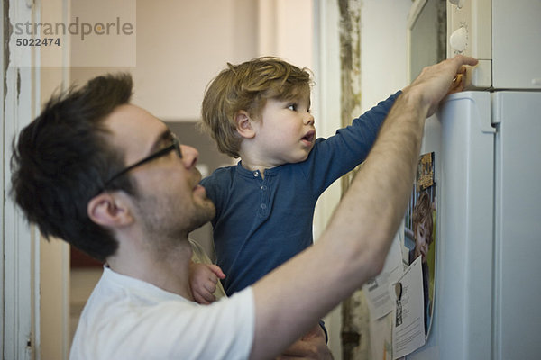 Kleinkind Junge hilft Vater mit der Mikrowelle